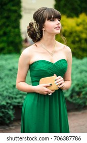 girl brunetka . Dressed in a beautiful green dress , ball . beautiful hair and make-up Golden purse - Shutterstock ID 706387786