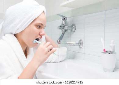 Girl Brushes Her Teeth Standing In Front Of A Tap With Water