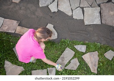 Girl Builder Laying And Grouting York Stone Paving Slabs Outdoors, DIY Home Patio Project , Finland Scandinavia, Landscaping Around A Wooden House, Hygge With Your Own Hands