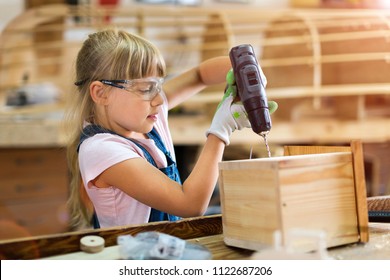 Girl Building Birdhouse In Garage