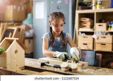 Girl building birdhouse in garage