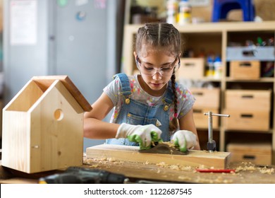 Girl Building Birdhouse In Garage