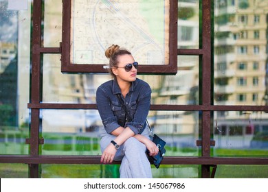 The girl at the bus stop in sunglasses
