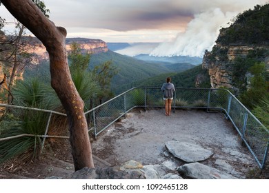 Girl At A Bushwalking Lookout With A View Over A Remote Bushfire And Smoke In The Blue Mountains, New South Wales, Australia.