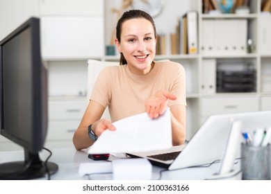 Girl Business Manager Working In A Large Company Examines The Documentation On Paper, Sitting At The Workplace In The ..office