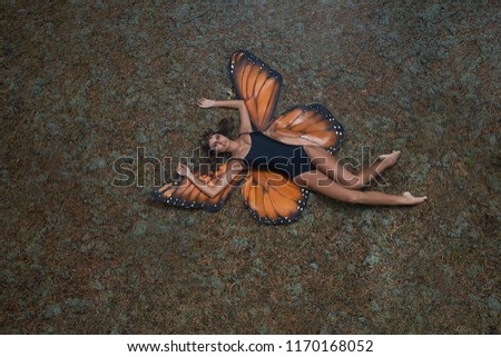 A girl in a butterfly suit lies on the ground