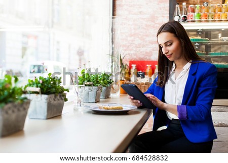 Girl in a cafe reads something on the tablet