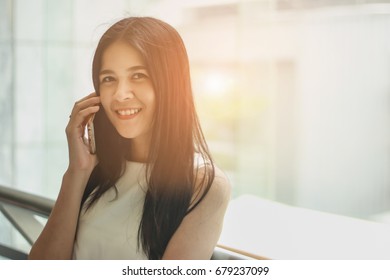 Girl Calling On Phone Land Line And Looking Outdoors Through A Window In The Living Room At Home