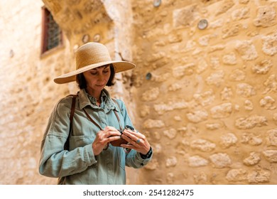 girl with a camera adjusts the camera. A stylish girl in a hat with a film camera stands on the street of an Arab city. film camera close up. adventures and travel. - Powered by Shutterstock