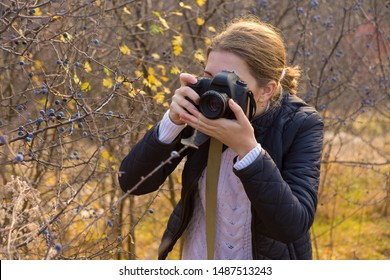 A Girl With A Camera In Her Hands In A Funny Pose Makes A Frame. Paparazi With A Camera In His Hands On An Outbreak In The Mountains.