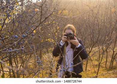 A Girl With A Camera In Her Hands In A Funny Pose Makes A Frame. Paparazi With A Camera In His Hands On An Outbreak In The Mountains.