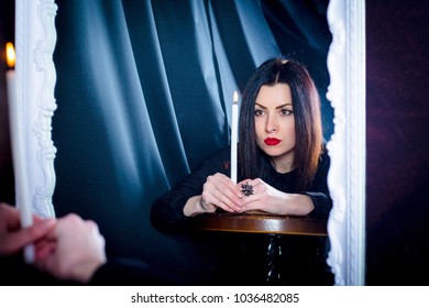 girl with a candle cast looks into her reflection in the mirror. Divination - Shutterstock ID 1036482085