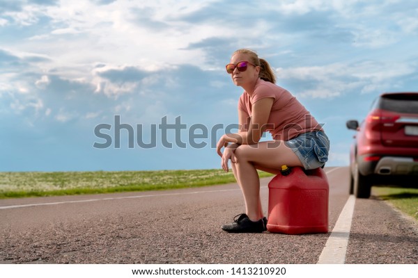 Girl with canister on country car road on\
sunny day. Blurred\
background.