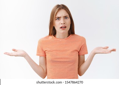 Girl cannot understand whats your problem. Pissed-off distressed young girlfriend in striped t-shirt raising hands sideways in dismay and disappointment, stare confused, puzzled what happened