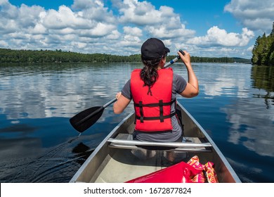 Girl canoeing on a beautiful lake wearing a red life jacket