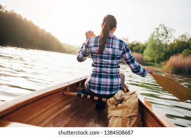 Girl canoeing. Rear view of travel woman rowing the boat at sunset.