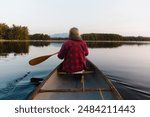 Girl canoeing wearing flannel on a lake in Northern Maine with views of Katahdin.