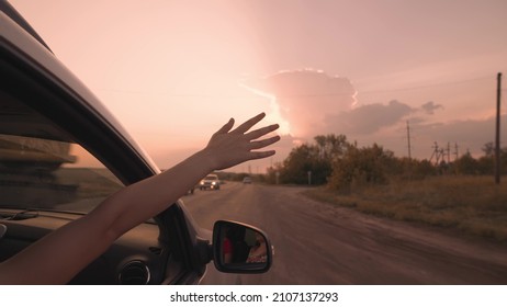 Girl From A Car Catches Wind With Her Hand At Sunset, Drive A Car On A Journey, Drive On An Asphalt Road, Enjoy Free Speed, Happy Family Life, Driver's Adventure On Vacation, Concept Of Carefree Trip