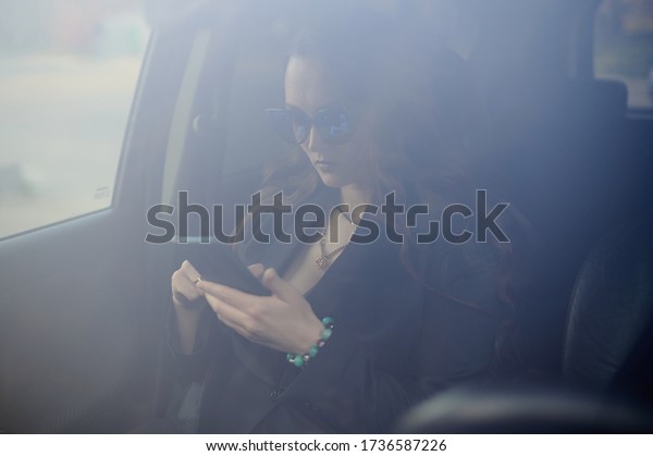 girl in a\
car with a phone in her hands and\
glasses