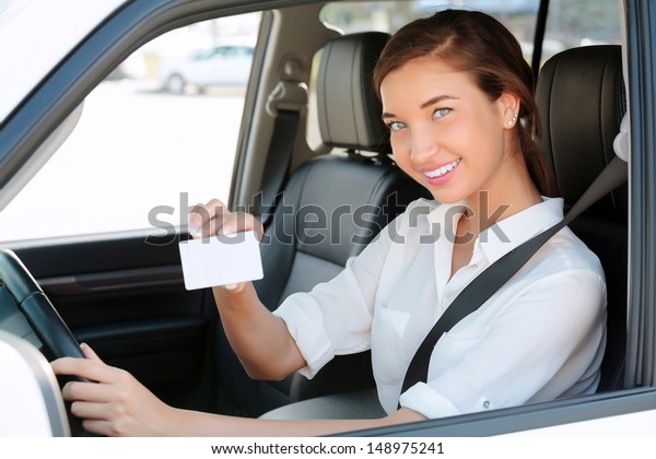 girl in a car showing an empty white card for your\
message 