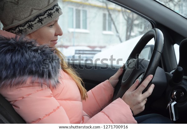Girl in car in winter. Woman in winter clother\
driving a car