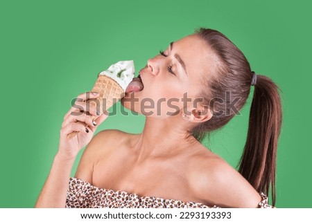 The girl carefully looks at the ice cream in the cone. On a green girl eats ice cream isolated background. The girl eats the taste of ice cream clipping. Light summer sundress on a girl eats ice cream