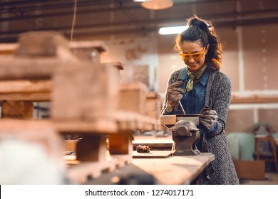 Girl in carpentry workshop doing wood job with protective glasses on. - Powered by Shutterstock