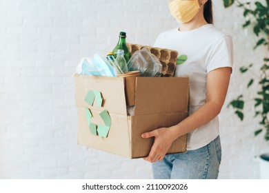 Girl carries box of garbage for recycling. - Shutterstock ID 2110092026