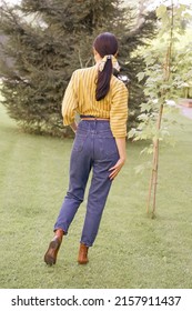 Girl In A Casual Outfit Posing In The Park. A Girl In A Yellow Blouse And Jeans With A Beautiful Elastic Band On Her Head. Stylish Image.