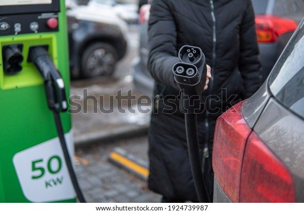 Girl to charge electric car. Hold in hand a cable to\
charge an electric car