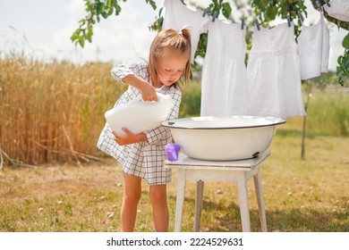 A girl in a checkered dress pours liquid detergent for washing white laundry into a bowl. Hypoallergenic eco-friendly Whitening Washing Powder - Shutterstock ID 2224529631