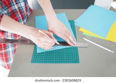 A girl in a checkered shirt cuts colored paper with a knife on a mock - Powered by Shutterstock