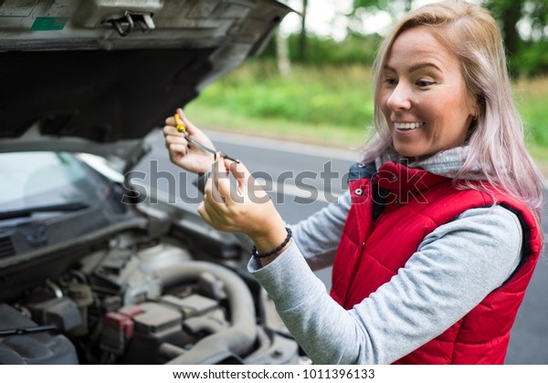 Girl checks the oil in\
the car\'s engine