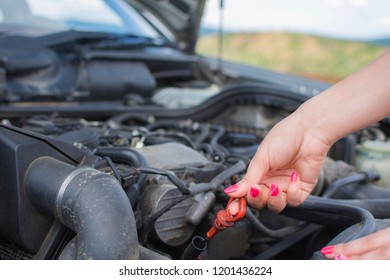 Girl checks the oil level in her car.  - Shutterstock ID 1201436224
