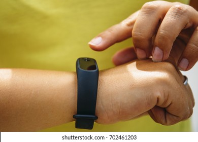 Girl Checks Pulse On Fitness Bracelet Or Activity Tracker Pedometer On Wrist, Toned