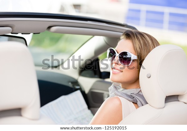 Girl checks the way with the help of the highway map\
sitting in the car