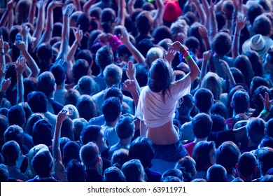 girl cheering with crowd and sitting upon the shoulders of her friend