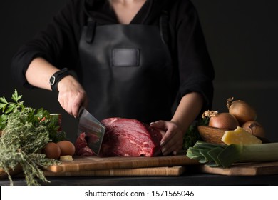 Girl Chef Chopping Meat With A Big Knife. Dark And Moody