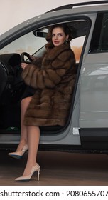 A Girl In A Chic Fur Coat And Light-colored Shoes Sits In A Car With An Open Door. Ukraine, Dnipro.  November 11, 2018