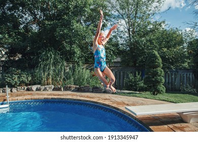 Girl Child Diving Jumping  In Water On Home Backyard Pool. Funny Cute Kid Enjoying And Having Fun In Swimming Pool On Summer Day. Summer Outdoor Water Activity For Kids. 