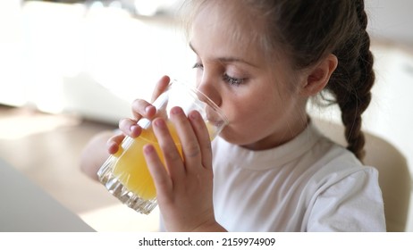 Girl Child Drinking Juice. Happy Family A Healthy Eating Kid Dream Concept. Daughter Girl Drinking Yellow Juice From A Glass Cup In The Kitchen. Child Drinking Indoor Fruit Juice