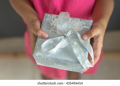 A Girl Child Holding A Gift Box.