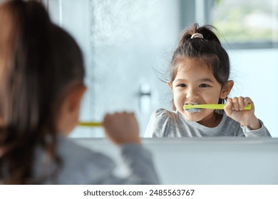 Girl child, mirror and brushing teeth in bathroom for hygiene with wellness, growth and gingivitis prevention in home. Young kid, reflection and tooth cleaning with development, foam and healthy gums - Powered by Shutterstock