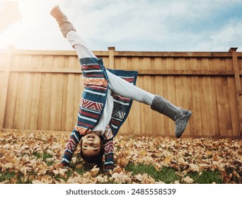 Girl, child and playing cartwheel outdoor in backyard for autumn fun, energy and flexible in development. Person, childhood and handstand on leaves in garden with activity, game and happy in home - Powered by Shutterstock