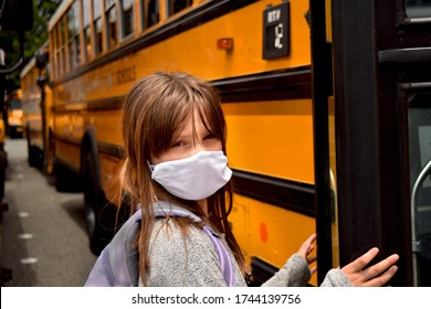 Girl, child, student with face mask boarding a school bus to classroom. For Education, Health, Medical, Environmental, Safety concepts regarding coronavirus, back to school, reopening, and facemasks. - Powered by Shutterstock