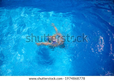 The girl is chilling from the summer heat in the pool, swimming and diving, enjoying a luxurious summer vacation, relaxing.