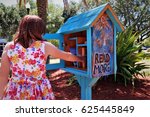 Girl choosing books from a Little Free Library in Florida