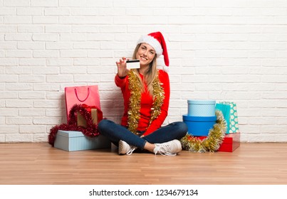 Girl With Christmas Hat And Many Gifts Celebrating The Christmas Holidays Holding A Credit Card