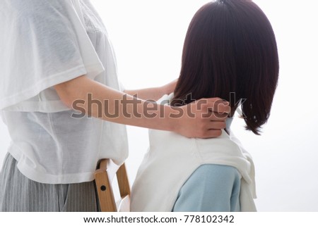 
A girl clapping her mother's shoulder
