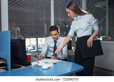 Girl in classic clothes at the office shows a colleague an error in the document with a pen and asks for a fix. - Shutterstock ID 725090737